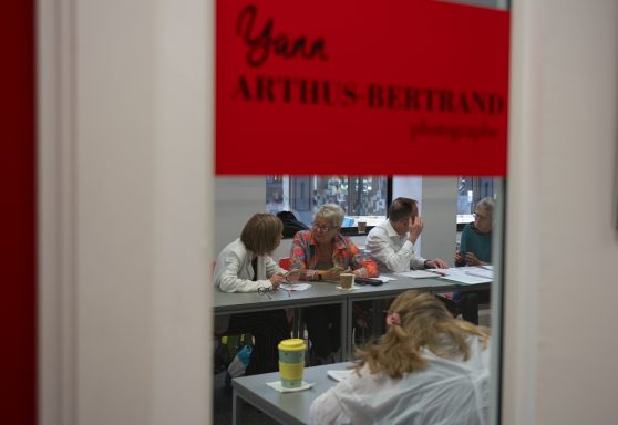 A group of people engaged in an activity inside a room with a red sign.